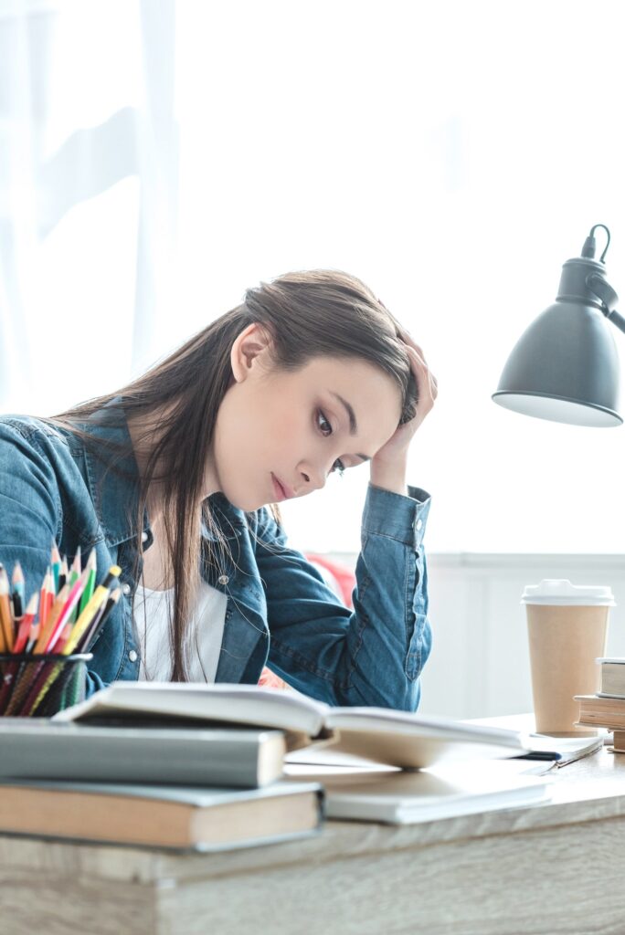 focused teenage girl taking notes and studying at desk